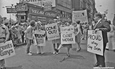 a group of people holding signs in the middle of a street with other people standing around