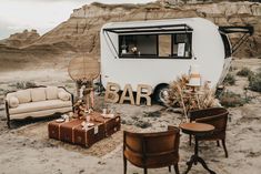 an rv is parked in the desert with furniture and decor around it that says bar