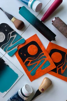 some art supplies are laying out on a white table with orange and blue paper cutouts