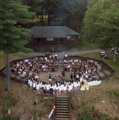 a large group of people standing in front of a wooden structure with steps leading up to it