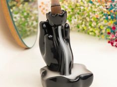 a black candle holder sitting in front of a mirror