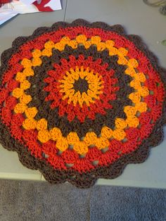 a crocheted doily with an orange, brown and yellow design on it