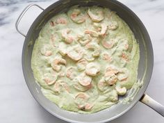 a pan filled with food sitting on top of a white marble counter next to a knife