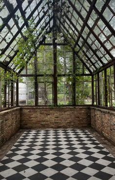 the inside of an old greenhouse with large windows and checkered flooring in black and white