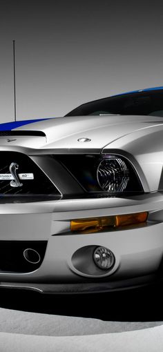 the front end of a silver mustang car with blue stripes on it's hood