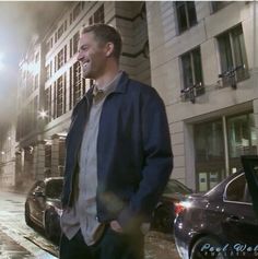 a man walking down the street in front of some cars