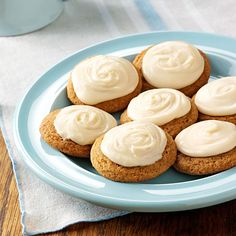 a plate filled with cookies covered in frosting on top of a wooden table next to a cup of coffee