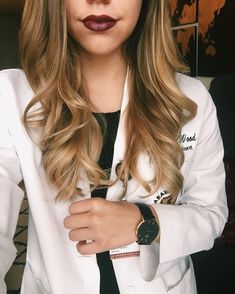 a woman in a white lab coat with her hands on her chest and wearing a watch