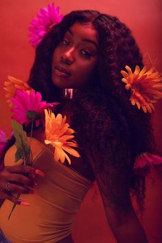 a woman with flowers in her hair posing for the camera while holding a flower bouquet