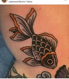 a fish tattoo on the side of a woman's thigh, with flowers around it