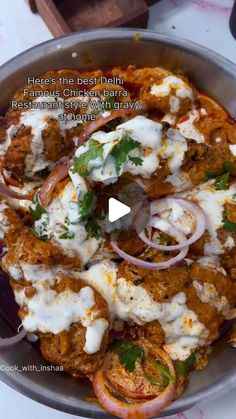 a pan filled with meat covered in sauce and onions on top of a white table