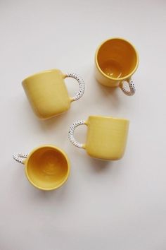 three yellow coffee cups sitting next to each other on top of a white countertop