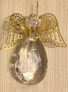 an angel ornament hanging from a wooden wall with a chain attached to it