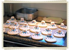 cookies decorated like snowmen are on a cookie sheet in front of a stove top