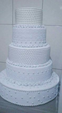 a large white wedding cake sitting on top of a table next to a tiled wall