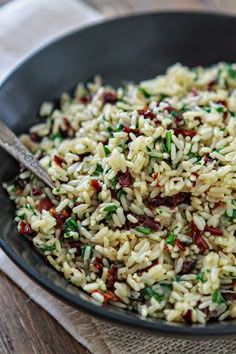 a bowl filled with rice and greens on top of a wooden table