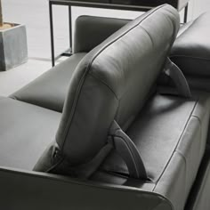 the back end of a gray couch with black leather upholster and arm rest