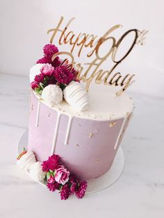 a birthday cake with pink flowers and gold lettering