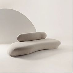 a white couch sitting on top of a white floor next to a round wall mirror