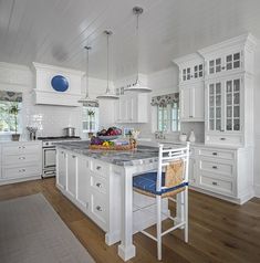 a large kitchen with white cabinets and an island in the middle, along with wooden floors