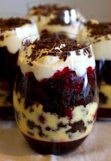 four desserts in small glasses with chocolate and cream toppings on the top, sitting on a table