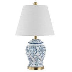 a blue and white porcelain lamp with a gold base on a white table cloth shade