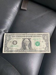 a one dollar bill sitting on top of a black leather chair