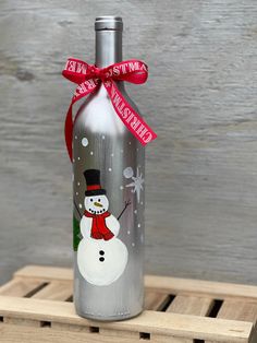 a bottle with a snowman painted on it and a red ribbon around the neck