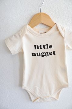 For the Little Nugget in your life. Sizing: the 3mo fits closer to a 0-3. We recommend sizing up if your little one is in between sizes - we all know those babies don't keep. Made with 100% organic cotton fabric Machine wash on low, tumble dry on cold Sewn in cotton label Sustainably printed using eco-friendly water-based inks Made in India Baby Onesie Ideas, Newborn Baby Outfits, Aunt Baby Clothes, Onesie Party, Mimi Life, Baby Announcement Onesie, Baby Wardrobe, Cute Onesies, Neutral Baby Clothes