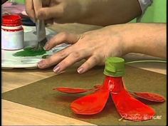 a woman is painting red flowers on a plate with green paint and a pair of scissors