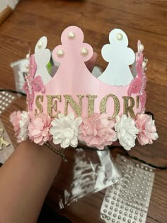 a pink princess crown with flowers and pearls on it's head is being held by someone