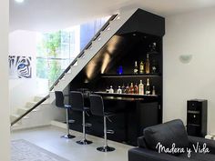 a living room filled with furniture and a bar next to a stair case on the wall