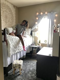 a woman sitting on top of a bed next to a small dog in a room