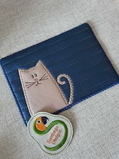 a patch with a cat on it sitting next to a blue piece of cloth that says happy birthday