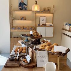 a table topped with lots of pastries on top of wooden trays next to shelves