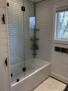 a white tiled bathroom with glass shower doors