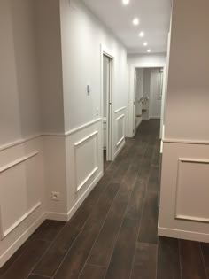 an empty hallway with white walls and wood floors