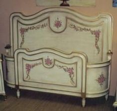 a white bed with pink flowers painted on the headboard and foot board in a bedroom