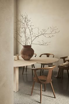 a vase with some flowers in it sitting on top of a wooden table next to chairs