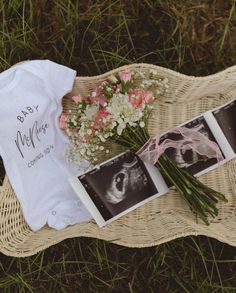 flowers and baby's t - shirt are laid out on a wicker mat