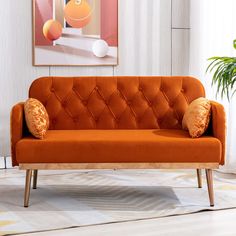 an orange couch sitting on top of a wooden floor next to a potted plant