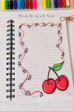 an open notebook with a drawing of two cherries on it