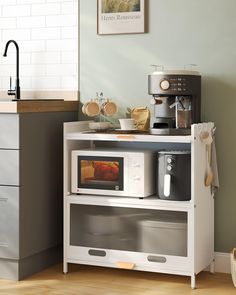 a microwave oven sitting on top of a white shelf next to a coffee pot and cup