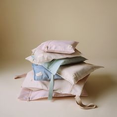 a pile of pillows sitting on top of each other in front of a beige wall