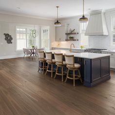 a large kitchen with an island and bar stools next to the stove top oven