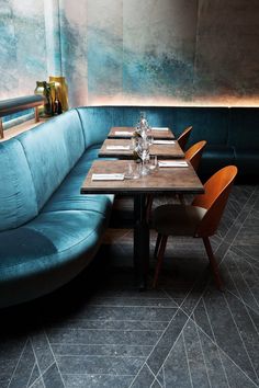 a restaurant with blue velvet booths and wooden tables