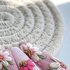 pink and white crocheted slippers with flowers on them sitting next to a rug