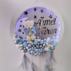 a white teddy bear sitting on top of a blue and silver balloon filled with balloons