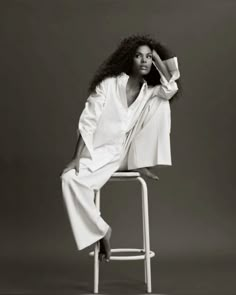 a black and white photo of a woman sitting on a stool