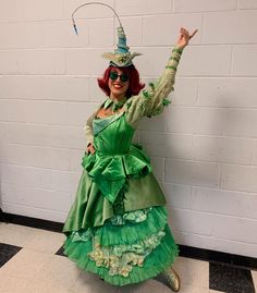 a woman dressed in green is posing for the camera with her arms up and hands out